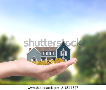 holding house representing home ownership and the Real Estate business holding house and coins