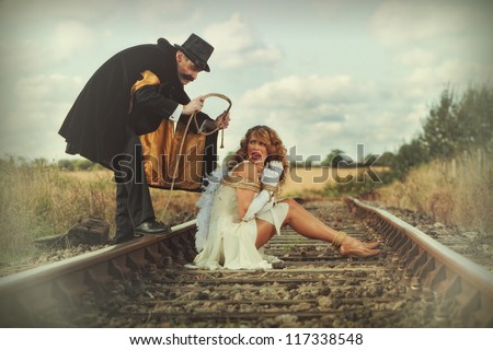 Pretty woman tied up on railway line by classic villain