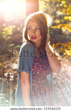 Beautiful woman in woods in autumn with sunlight coming through trees