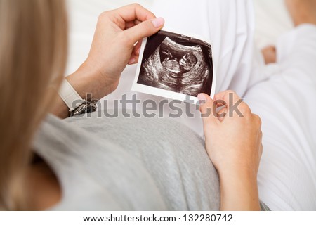 Pregnant woman looking at ultrasound scan of baby, close up of scan