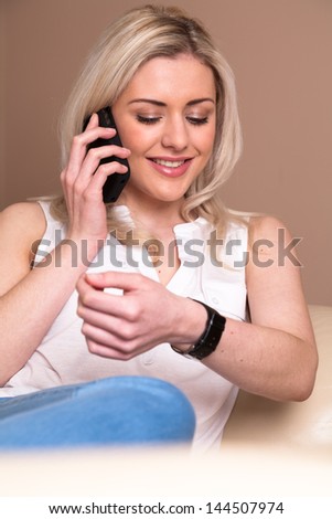 Young woman at home talking on phone and looking at watch