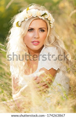 Whimsical image of beautiful woman in field with flowers in hair