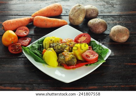 A piece of flank steak baked with vegetables isolated on wood background with vegetables