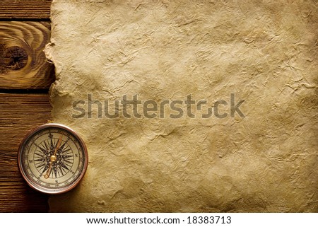 A ancient kit of a sailor consisting of a compass on old yellowish paper.