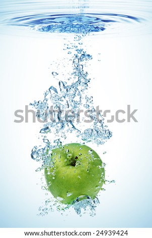 Green apple under water with a trail of transparent bubbles.
