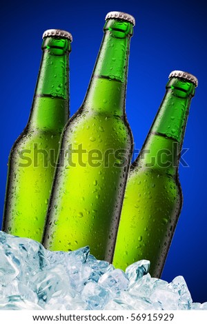A beer bottle sitting in a container of ice on blue background
