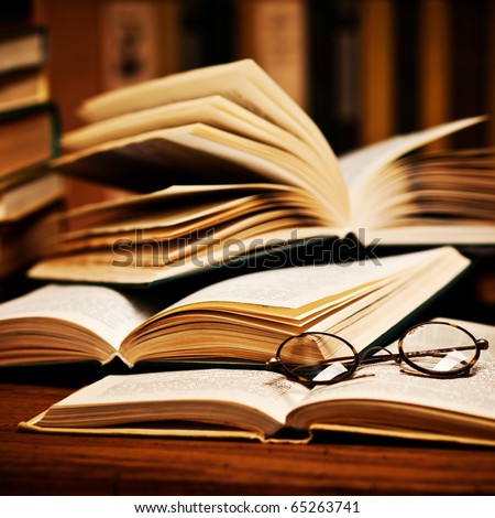 opened book, lying on the bookshelf with a glasses - stock photo