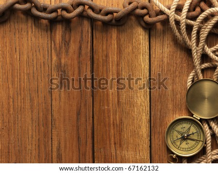 Compass, rope and chain on wooden board