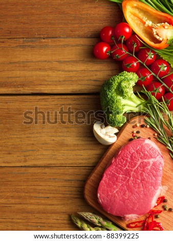 Raw Steak with green asparagus and vegetables on wooden board