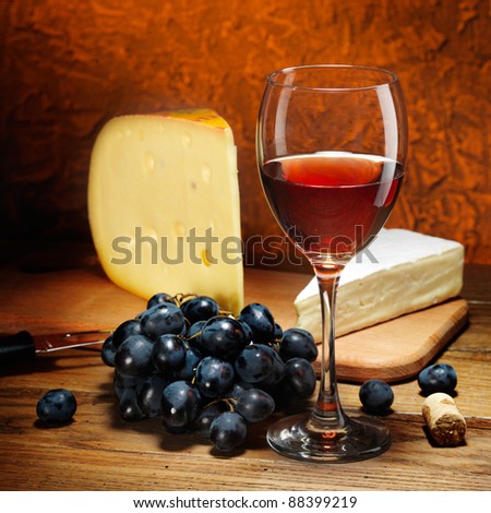 Still-life with cheese, grapes and glass of red wine.