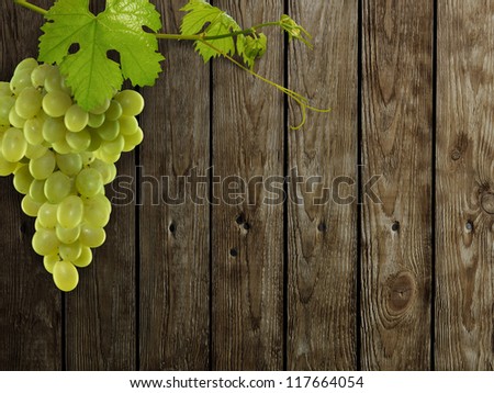 Fresh green grapes with leaves on wood background