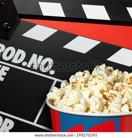 Clapper board and popcorn box on red background
