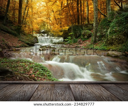 Autumn creek woods with yellow trees foliage and rocks in forest mountain and wood pier