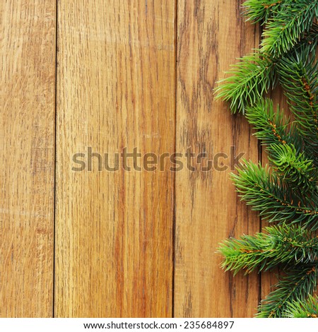 Decorated Christmas tree border on wood paneling with gold baubles and bells, a decorative Xmas gift wrapped in a golden bow, holly and beads with copyspace for your seasonal greeting