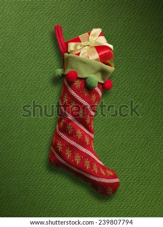 Christmas sock with red gift box on green paper background