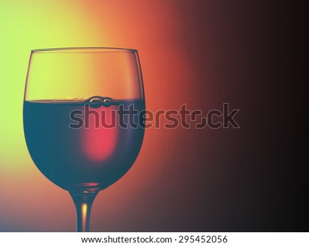 glass of red wine on dark red background.Filtered image: cool cross processed vintage effect.