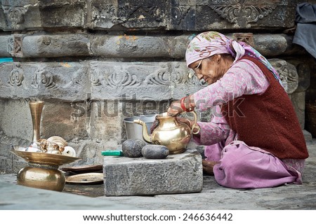 Naggar, INDIA - JULY 17: Old Indian woman cleans the dishes out of the temple. Special dishes which make offerings to God in the temple. July 17, 2013 in Naggar, Kullu Valley, Himachal Pradesh, India