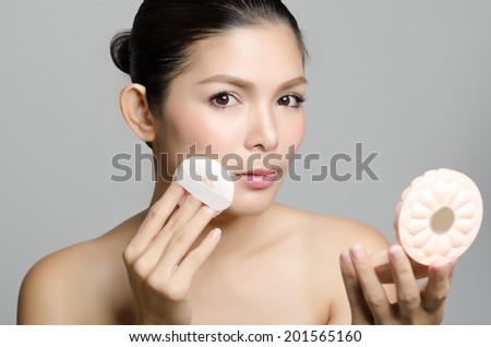 Woman applying cosmetic powder puff on her face