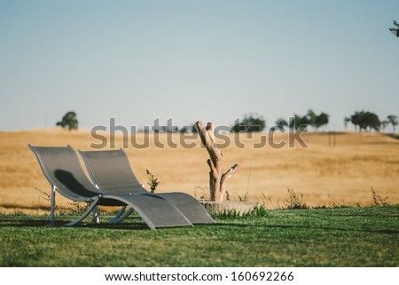 A relaxing country scene in Alentejo, Portugal, with a fantastic landscape view. Includes two lounge chairs and a small tree trunk.