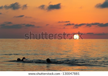 Majestic sunset over the Black Sea with swimmers on foreground