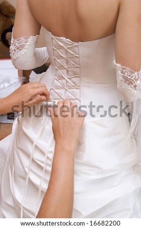 Female hands tightening a corset to the bride.