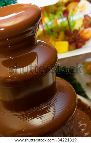 Chocolate fountain against fruit