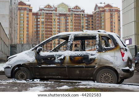 The burnt down car in snow. The second day after a fire.