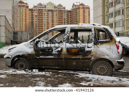 The burnt down car in snow. The second day after a fire.