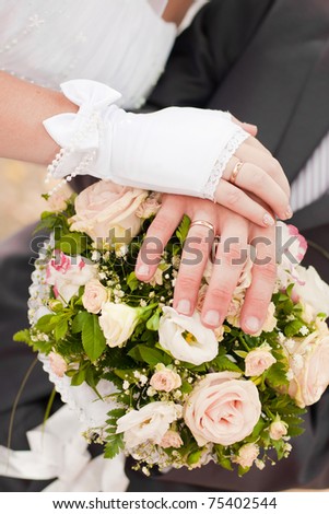 Hands of a newly-married couple with rings on a bouquet