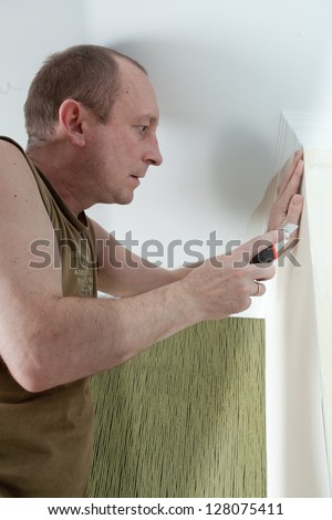 the man glues wall-paper on wall
