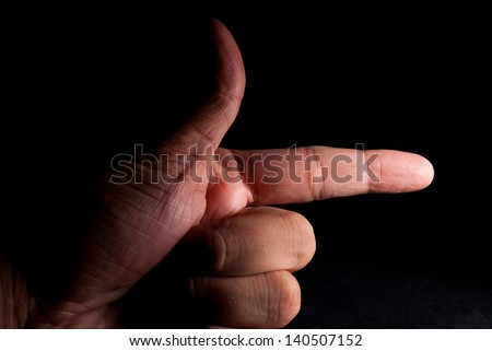 Hand making finger gun gesture, over black background. Gesture thumb up then down forefinger out like gun. Bullying and abuse concept.