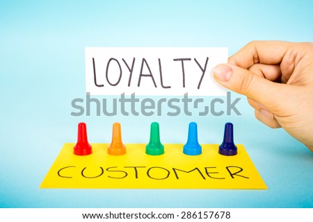 Hand with loyalty message over multicolored pawn pieces and the word customer. Customer loyalty concept.