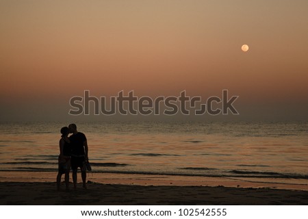 Love couple at sunset with a full moon