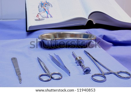 Surgical instruments on a blue background, with a medical textbook in the background.