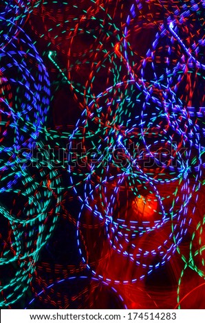 Abstract blue, red, purple and green neon spirals and an orange light on a black background