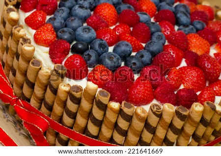 Fresh and fruity birthday cream cake with biscuits, strawberries, raspberries and blueberries.