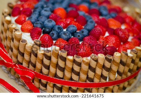 Fresh and fruity birthday cream cake with biscuits, strawberries, raspberries and blueberries.