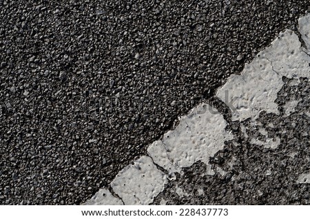 A dark asphalt pavement texture with aged and weathered horizontal traffic sign painted with white color