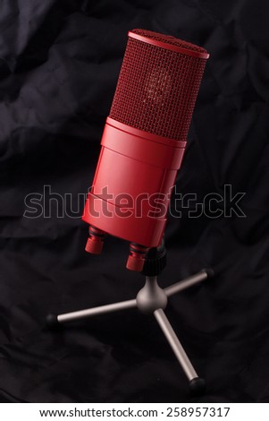 Red professional studio microphone on a stand with soft black background