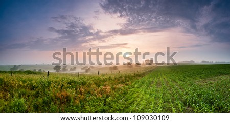 Sun peaking through the clouds over a pasture and corn field
