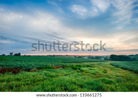 Sunrise with cloudscape over farm ground
