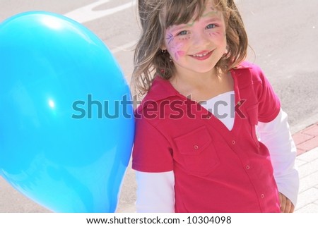 Five-year-old girl with pink and fancy make-up on his face, stands near the road with a large blue ball.