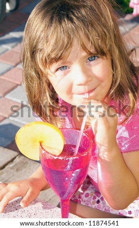 The girl on holiday in a bright sunny day, she drinks through a tube of pink glasses.