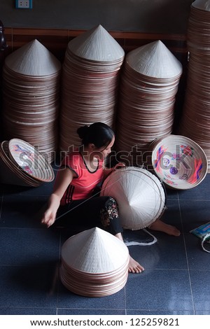HANOI, VIETNAM - OCTOBER 23: Vietnamese woman sitting sewing hats in a traditional village in Vietnam October 23, 2010. Conical hat is an traditional item of ethnic Vietnam