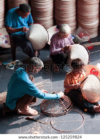 HANOI, VIETNAM - OCTOBER 23: unidentified vietnamese a family sitting sewing hats in a traditional village in Vietnam October 23, 2010. Conical hat is an traditional item of ethnic Vietnam