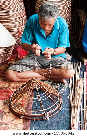 HANOI, VIETNAM - APRIL 21: Vietnamese man sitting sewing hats in a traditional village in Vietnam April 21,2013. Conical hat is an traditional item of ethnic Vietnam