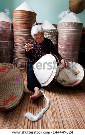 HANOI, VIETNAM - APRIL 21: Vietnamese woman sitting sewing hats in a traditional village in Vietnam April 21,2013. Conical hat is an traditional item of ethnic Vietnam