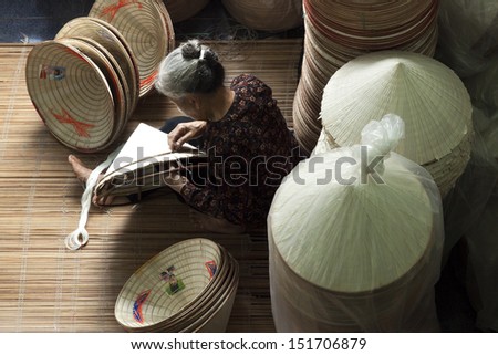 HANOI, VIETNAM - APRIL 21: Vietnamese woman sitting sewing hats in a traditional village in Vietnam April 21,2013. Conical hat is an traditional item of ethnic Vietnam