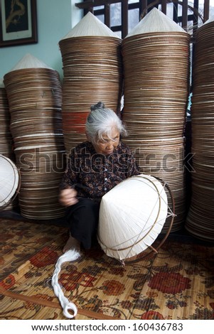 HANOI, VIETNAM - APRIL 21: Vietnamese woman sitting sewing hats in a traditional village in Vietnam April 21,2013. Conical hat is a traditional item of ethnic Vietnam