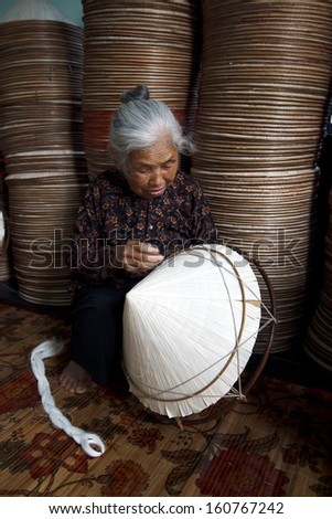 HANOI, VIETNAM - APRIL 21: Vietnamese woman sitting sewing hats in a traditional village in Vietnam April 21,2013. Conical hat is a traditional item of ethnic Vietnam